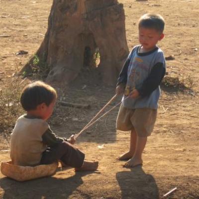 Enfants Hmong jouant à la luge sur terre